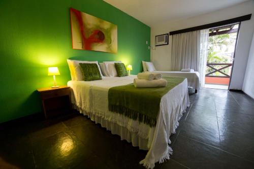 a green bedroom with a bed with a teddy bear on it at Pousada Vila do Sol in Búzios