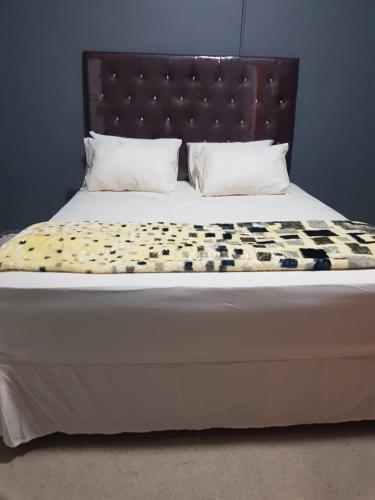 a bed with a headboard and pillows on it at SALAMA LODGE in Cape Town