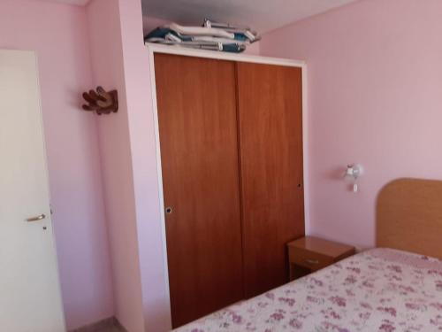 1 dormitorio con 1 cama y armario de madera en Complejo Evelin en Las Grutas