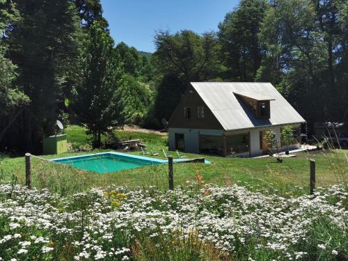 a house with a swimming pool in a field with flowers at Hostal La Casita del Bajo in Curacautín