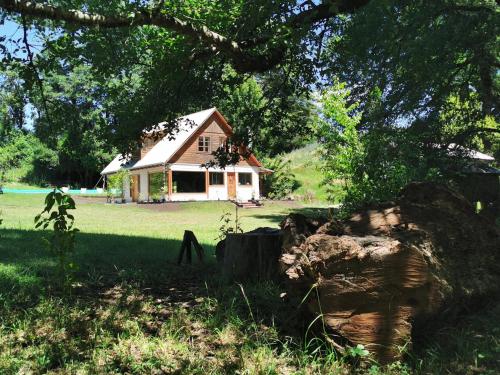 una casa en medio de un campo con un árbol en Hostal La Casita del Bajo, en Curacautín