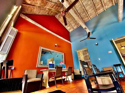 comedor con pared de color naranja, mesa y sillas en Hotel El Viajero Centro, en Cartagena de Indias