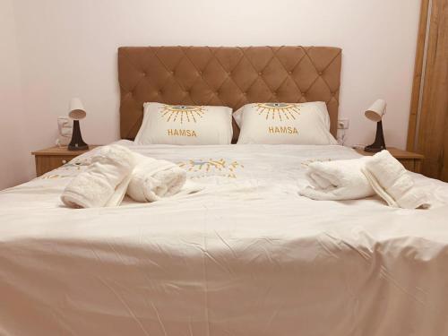 Una cama con sábanas blancas y almohadas. en Uyut apartments en Majdal Shams