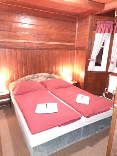 a bedroom with a bed with red sheets and two certificates at Hotel Diana in Špindlerův Mlýn
