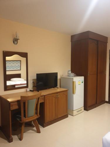 una stanza con una scrivania con una televisione e un frigorifero di Sunview Place a Centro di Pattaya