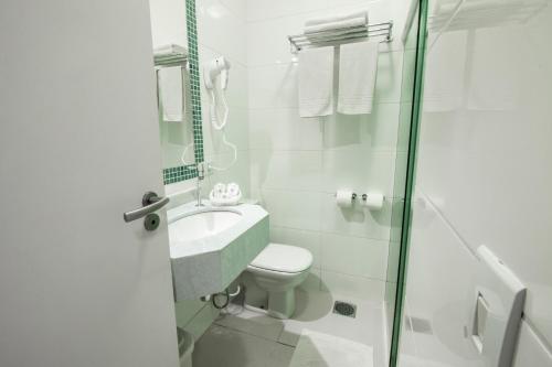 a bathroom with a toilet and a sink and a shower at Apart Hotel Porto Kanoas in Bertioga