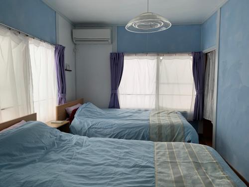 two beds in a bedroom with blue walls and windows at Cozy Penguin House Bibai in Bibai