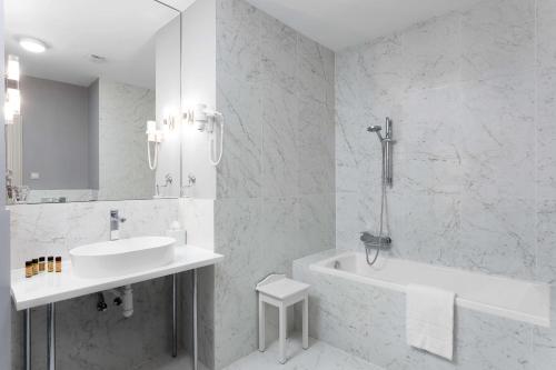 a white bathroom with a tub and a sink and a bath tub at Károlyi Kastély Hotel & Restaurant in Fehérvárcsurgó
