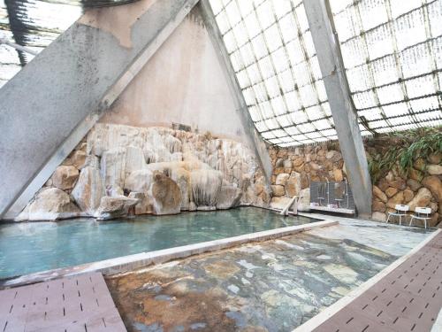 ein Pool in einem Gebäude mit einer Felswand in der Unterkunft HOTEL SHIRAHAMAKAN in Shirahama