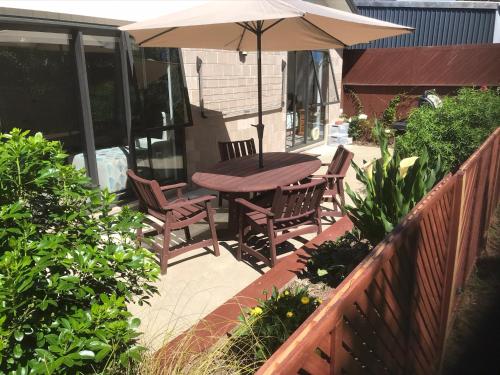 a patio with a table and chairs and an umbrella at Baybell Lodge in Tauranga