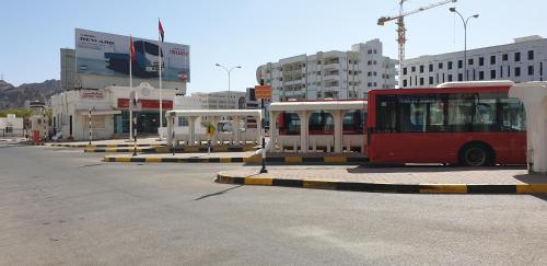 a red bus is parked in a parking lot at ALWAFA HOTEL FLATS in Ruwī