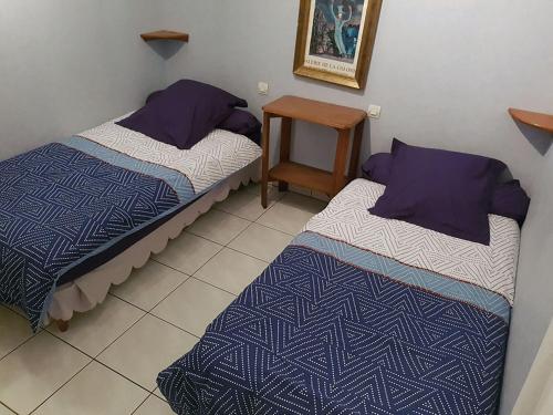 two beds in a small room with a table at Gîte Santenay les Bains in Saint-Sernin-du-Plain