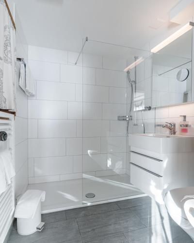 a white bathroom with a shower and a sink at Chalet Sunna Höckli - Pistennah und Ruhig mit Panoramablick in Arosa