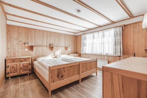 a bedroom with a large bed and wooden walls at Chalet Sunna Höckli - Pistennah und Ruhig mit Panoramablick in Arosa
