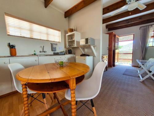cocina con mesa de madera y sillas blancas en Koppie Cottage en Prince Albert