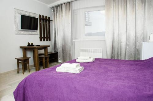 uma cama roxa com toalhas por cima em Ластівчине гніздо em Shayan