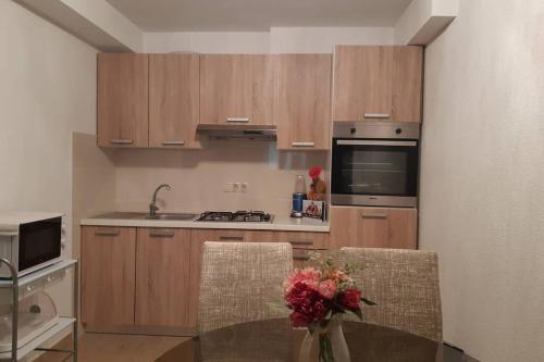 a kitchen with wooden cabinets and a table with a vase of flowers at Apartmant Angel Wings in Omiš