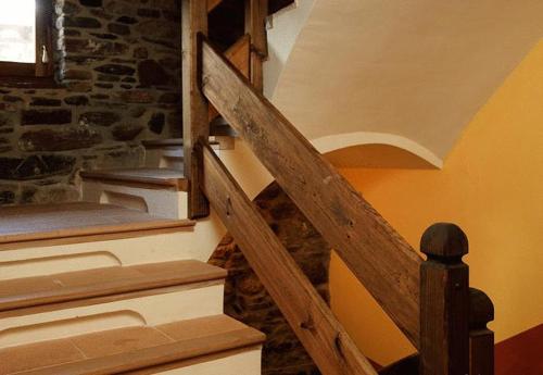 a wooden staircase in a room with a stone wall at Casa Rafeleta Hotel in Plan