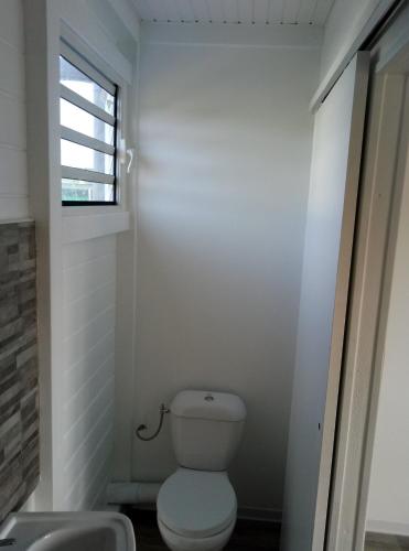 a white bathroom with a toilet and a window at Séjournez au coeur des Tropiques Bungalow 2 chambres avec Piscine proche de la mer in Sainte-Anne
