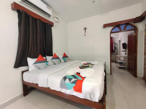 Schlafzimmer mit einem Bett mit weißer Bettwäsche und Kissen in der Unterkunft Shelton Guest House in Baga