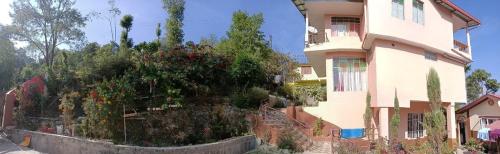 a large building with a garden next to a house at SAI´S GRACE in Kalimpong