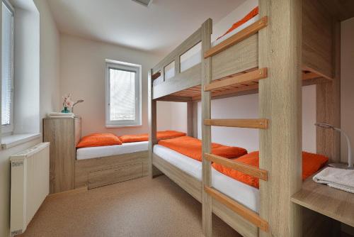 Pokój z łóżkiem piętrowym z 2 łóżkami piętrowymi i pomarańczowymi poduszkami w obiekcie Rekreační domek Kobylnice Lipno w mieście Lipno nad Vltavou