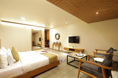 a bedroom with a bed and a tv and a chair at Tara Suns in Vadodara