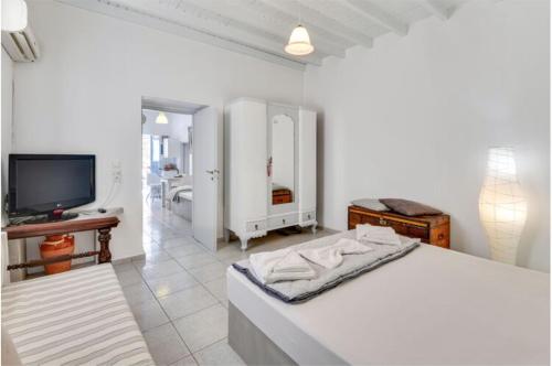 a white bedroom with a bed and a television at Traditional Cycladic House in Tripití