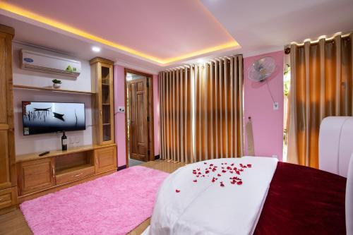 1 dormitorio con 1 cama con alfombra rosa y TV en Kim Hoàn Hotel Phan Rang, en Phan Rang