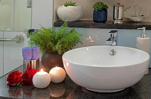 a bathroom with a white sink and candles on a counter at 185 on BEACH Boutique Suites in Gordonʼs Bay