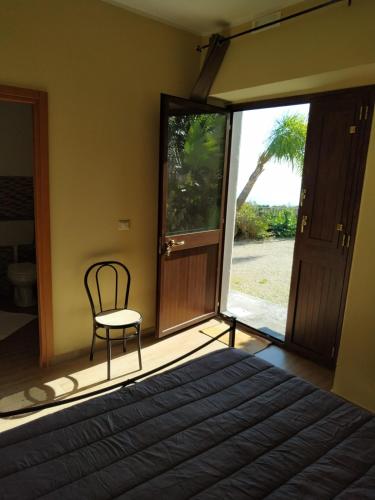 a bedroom with a bed and a chair and a window at Tenuta la Timpa Vela rooms And pool in Acireale