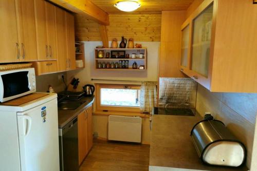 una pequeña cocina con armarios de madera y nevera blanca. en Chata pri potoku Tále en Bystrá