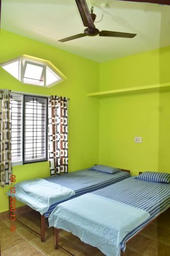 two beds in a room with green walls and a ceiling at Doctors Heritage Lodge in Sringeri