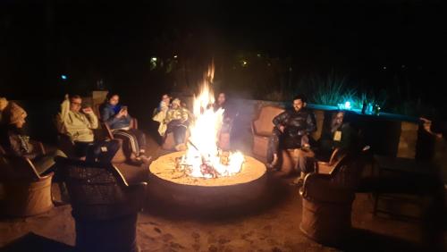 a group of people sitting around a fire pit at night at Ranthambhore Bagh Dwar Camp in Khilchipur