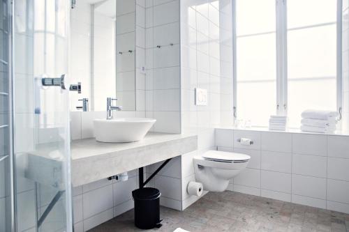 uma casa de banho branca com um lavatório e um WC em Kalk Hotel em Visby