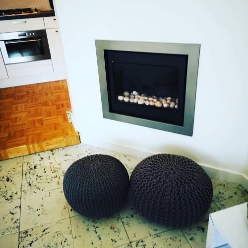 two round black ottomans in front of a fireplace at Fleuri Westende in Middelkerke