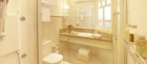 a bathroom with a toilet and a sink and a mirror at Jurere Il Campanario Villaggio Resort in Florianópolis