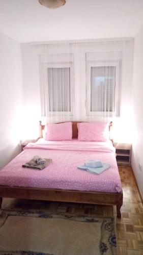 a bedroom with a large bed with pink sheets at Apartman Jevtić 2 in Gornja Toplica