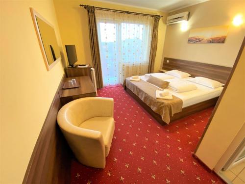 a hotel room with a bed and a chair at Vila Cristal in Baile Felix