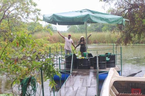 two people standing on a boat with an umbrella at Wilpattu Green Cabin in Achchamulai
