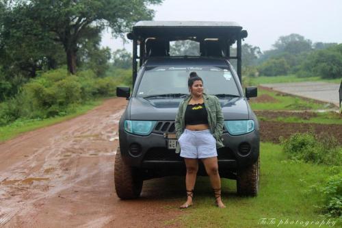 a woman standing in front of a car on a dirt road at Wilpattu Green Cabin in Achchamulai