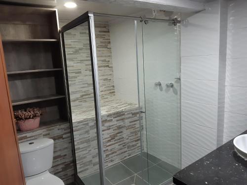 a bathroom with a glass shower with a toilet at Aparta Hotel mi Casa in Manizales