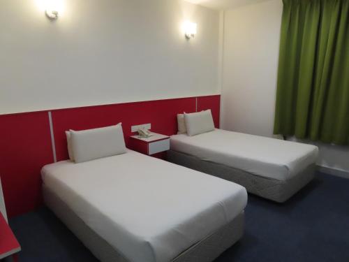 a room with two beds and a green curtain at Akar Hotel Kampung Baru in Kuala Lumpur