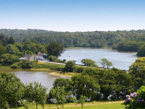 a large lake with a house and a boat in it at Domaine De Kerstinec/Kerland in Riec-sur-Bélon