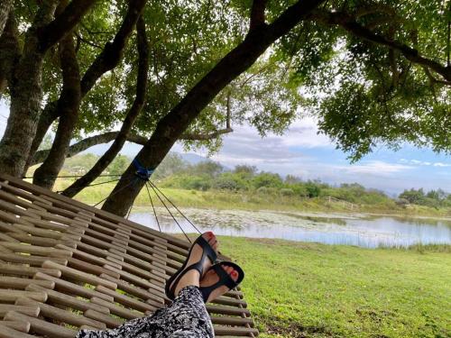 a person sitting on a swing near a lake at ECO Lodge Villa Villekula in The Crags