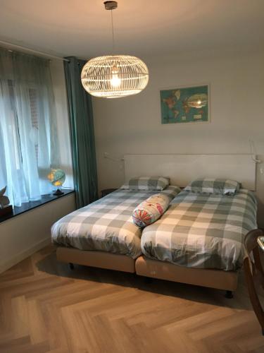 a bedroom with two beds and a chandelier at Strandhuis in Egmond aan Zee