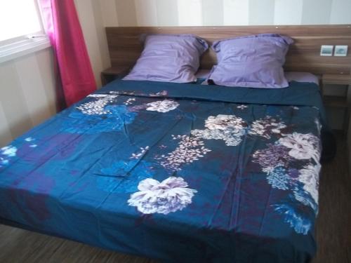 Una cama con una colcha azul con flores. en camping aire du gros pré, en Lesseux