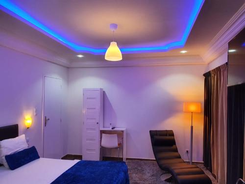 a bedroom with a bed and a blue light on the ceiling at Résidence Blue hôtel in Thiès