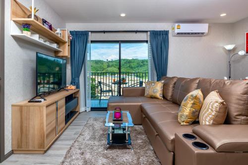 salon z brązową kanapą i telewizorem w obiekcie The Title Residencies Naiyang Beach w mieście Nai Yang Beach