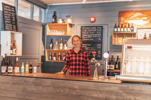 a man standing behind a counter in a bar at Skårungen - Hotel, Cabins and Camping in Kabelvåg